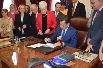 Governor Malloy signs legislation at his desk